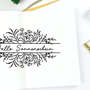 May include: A black and white illustration of a floral wreath with the text "Hallo Sonnenschein" in the center.