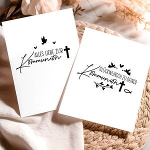 Peut inclure: Deux cartes blanches avec de l'encre noire. La premi&egrave;re carte dit "Alles Liebe zur Kommunion" avec une colombe et une croix. La deuxi&egrave;me carte dit "Gl&uuml;ckwunsch zu deiner Kommunion" avec une croix, des colombes et des accents floraux.