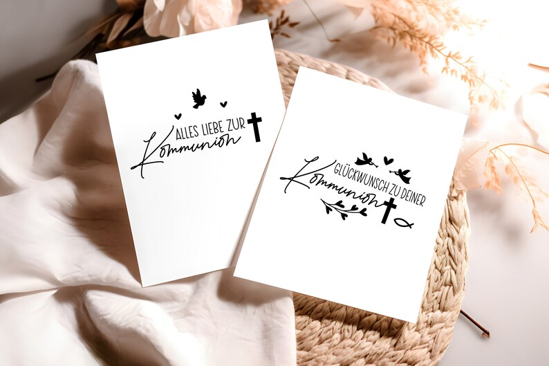 Peut inclure: Deux cartes blanches avec de l'encre noire. La premi&egrave;re carte dit "Alles Liebe zur Kommunion" avec une colombe et une croix. La deuxi&egrave;me carte dit "Gl&uuml;ckwunsch zu deiner Kommunion" avec une croix, des colombes et des accents floraux.