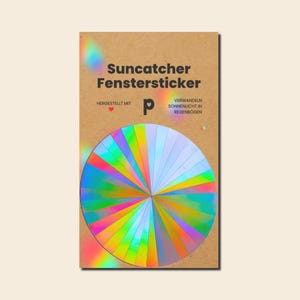 Könnte beinhalten: Ein kreisförmiger, holografischer Fensteraufkleber auf einer braunen Pappunterlage. Der Text lautet Suncatcher Fenstersticker, HERGESTELLT MIT und VERWANDELN SONNENLICHT IN REGENBÖGEN. Der Aufkleber zeigt ein radiales Muster aus irisierenden Farben.