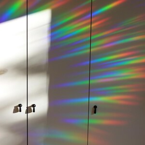 Pu&ograve; includere: Due ante di armadio bianche con pomelli neri. Le ante sono ricoperte da un film a prisma arcobaleno che crea un motivo colorato e iridescente.