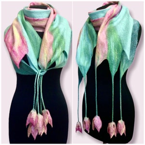 May include: A teal and pink felted wool scarf with long tassels that resemble pink flowers. The scarf is draped over a black mannequin.