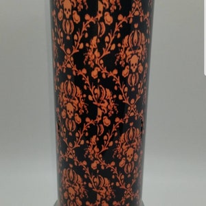 May include: A black and orange glass lamp with a skull and floral pattern. The lamp has a silver base.