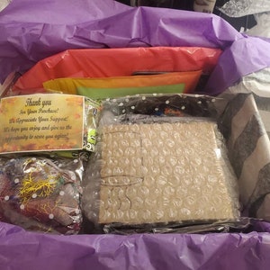May include: A purple and white gift box filled with items wrapped in bubble wrap and tissue paper. A thank you note reads "Thank you for your purchase! We appreciate your support! We hope you enjoy and give us the opportunity to serve you again."