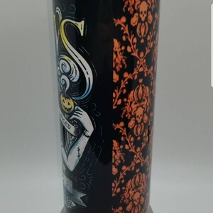 May include: A black and orange stainless steel tumbler with a Halloween-themed design. The design features a skull and crossbones, a pumpkin, and the text "Spiced".