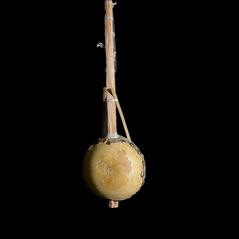 May include: A traditional stringed musical instrument with a gourd body and a wooden neck. The gourd is covered in leather and has metal accents. The neck is wrapped in string.