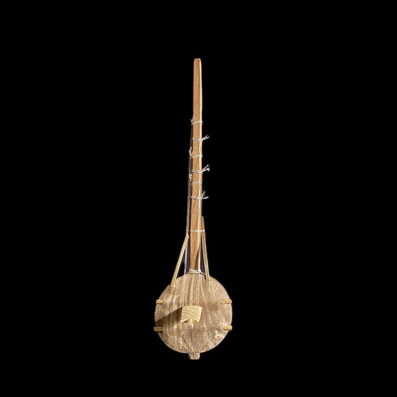 May include: A wooden musical instrument with a round body and a long neck. The instrument is made of natural wood and has a simple design.