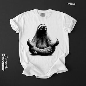 May include: A white short-sleeved t-shirt featuring a black and white graphic of a sloth sitting in a meditative lotus position. The shirt has a crew neckline and the text "White" is printed in the top right corner, with "Gerard Studio" on the left.
