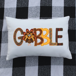 May include: White pillow with the word "GOBBLE" in colorful plaid and patterned letters. A cartoon turkey is in the middle of the word.