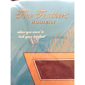 Puede incluir: Un paquete vintage de medias Fine Feathers con fondo azul y letras doradas. El texto dice "Fine Feathers Hosiery" y "when you want to look your loveliest".