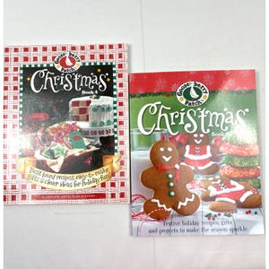 Puede incluir: Dos libros de cocina de Navidad de Gooseberry Patch con cubiertas a cuadros rojos y blancos. El libro de la izquierda se titula "Christmas" con el subtítulo "Book 4" y presenta un fondo a cuadros rojos y blancos con una variedad de imágenes con temática navideña. El libro de la derecha se titula "Christmas" con el subtítulo "Book" y presenta un fondo a cuadros rojos y blancos con un hombre de jengibre y otras imágenes con temática navideña.