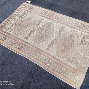 May include: A beige and brown patterned rug with a geometric design. The rug has a light beige background with brown and pink accents.