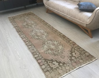 Może przedstawiać: Jasnobrązowy i beżowy dywanik do korytarza z kwiatowym wzorem. Dywanik ma frędzlowane brzegi i leży na jasnej drewnianej podłodze.