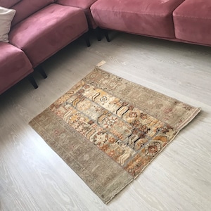 Könnte beinhalten: Ein beige-brauner Teppich mit geometrischem Muster. Der Teppich liegt auf einem hellen Holzboden.