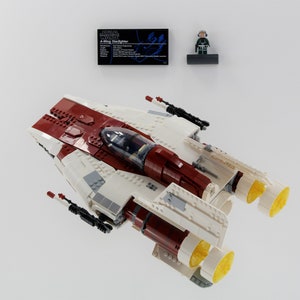 May include: A white and red LEGO Star Wars A-wing Starfighter with a yellow engine and a minifigure of a pilot.