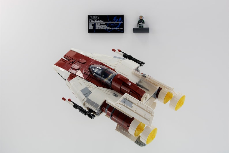May include: A white and red LEGO Star Wars A-wing Starfighter with a yellow engine and a minifigure of a pilot.