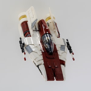May include: A white and red Lego spaceship with black details and clear cockpit windows.