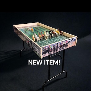 May include: A wooden tabletop horse racing game with a green felt playing surface and colorful plastic horses. The game is set up on a black metal folding table. The text "NEW ITEM!" is printed below the table.