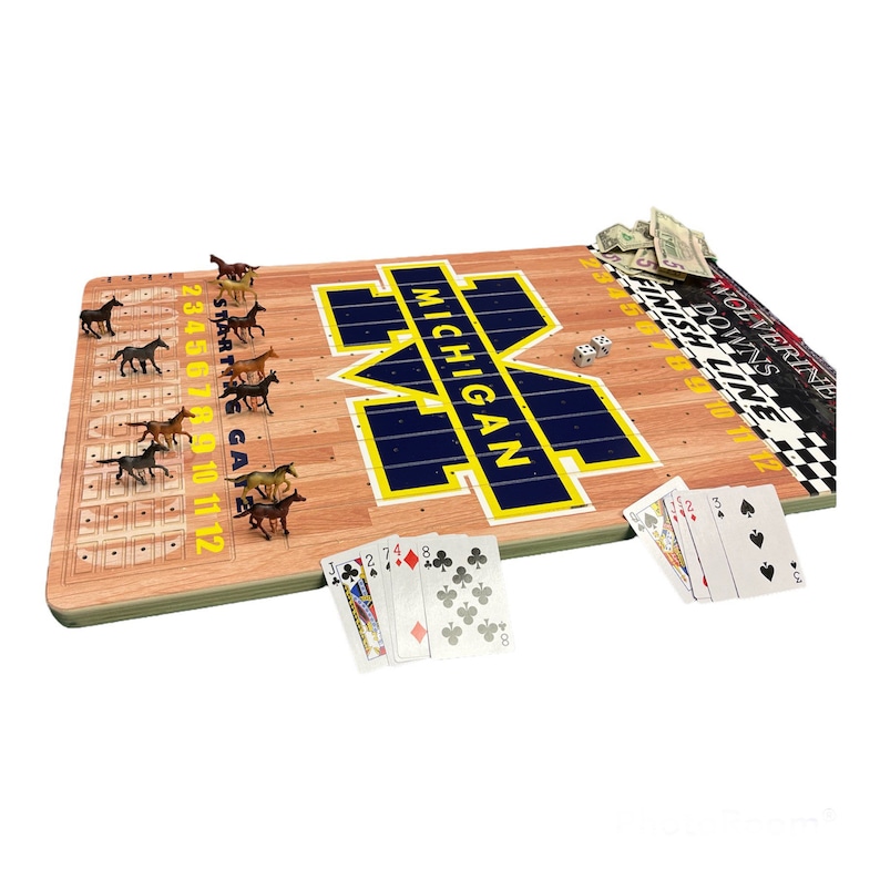 May include: A wooden game board with a blue and yellow Michigan Wolverines logo. The board has a race track with 12 spaces and a starting gate. There are small plastic horses on the track. The game also includes a deck of cards, dice, and play money.
