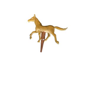 May include: A small, brown plastic horse figurine with a gold-colored metal base. The horse is in a running pose with its head turned to the side.