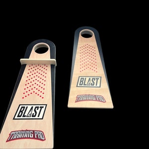 May include: Two wooden game boards with black and white borders and red dots. The boards have a hole in the top and the text "BLAST TRAINING PRO" printed on them.