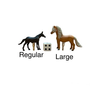 May include: Two toy horses, one black and one brown, standing on a white surface. The black horse is labeled "Regular" and the brown horse is labeled "Large". A white die with black dots is between the horses.