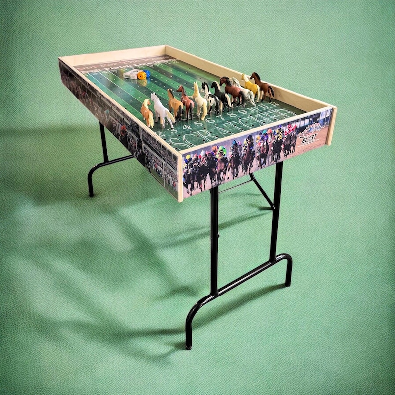 May include: A wooden tabletop horse racing game with a green felt track and colorful plastic horses. The game is set up on a black folding table with a green felt surface. The game includes a dice and a finish line.