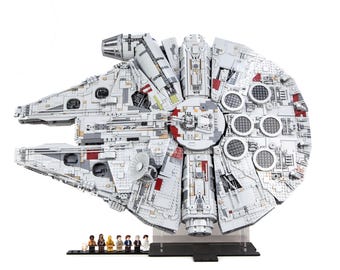 Può includere: Un modello dettagliato dell'astronave Millennium Falcon, principalmente bianco con accenti grigi e rossi. Il modello presenta dettagli intricati ed è esposto su un supporto trasparente. Piccole figure di personaggi sono allineate davanti al modello.