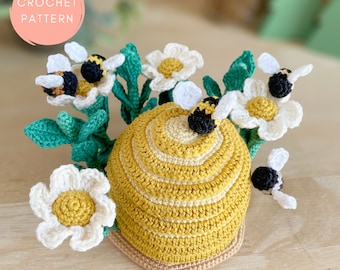 Peut inclure: Patron de crochet pour une ruche avec des abeilles et des marguerites. La ruche est jaune et marron, les abeilles sont noires et jaunes, et les marguerites sont blanches.