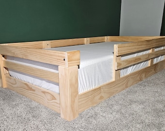 May include: A wooden toddler bed frame with a white mattress and safety rails. The bed frame is made of natural wood and has a simple design.