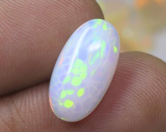 May include: An oval-shaped white opal gemstone featuring a smooth, polished surface with vibrant flashes of neon green and orange color play throughout the stone, showcasing a distinct play-of-color effect against a milky, translucent base.