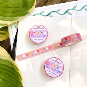Puede incluir: Dos rollos de cinta washi floral rosa con el texto "average art hoe" y "flower washi tape 15mm x 10m" en las etiquetas.