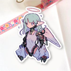 May include: A sticker featuring a stylized anime-inspired character with a halo, wings, and robotic elements. The character has light blue hair and wears a light purple outfit. The sticker is on a white background with floral patterned tape.