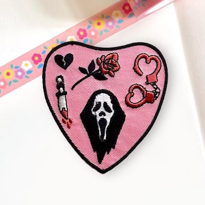 May include: Pink heart-shaped embroidered patch with a black and white ghost face, a red rose, a broken heart, and red handcuffs with a heart charm.