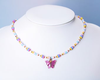 May include: A colorful beaded necklace with a pink butterfly charm. The necklace is made with small, round beads in shades of pink, blue, yellow, and white.