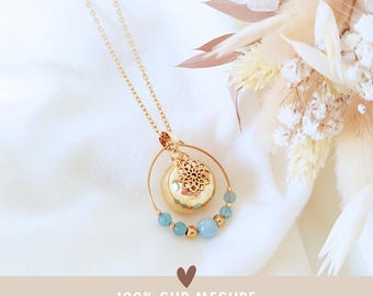 Könnte beinhalten: Eine goldfarbene Halskette mit einem Anhänger mit filigranem Design und einer goldfarbenen Kugel. Die Halskette hat eine zarte Kette und ist mit hellblauen Perlen verziert. Der Text "100% SUR MESURE entièrement personnalisable" ist ebenfalls vorhanden.