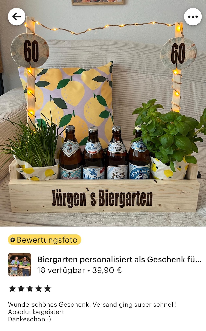 May include: A wooden crate with the text "J&uuml;rgen's Biergarten" on the front. The crate is filled with four bottles of beer, two potted plants, and a lemon-patterned pillow. Two wooden poles with the number "60" on them are in the background.