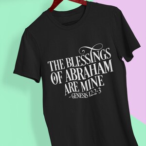 Puede incluir: Camiseta negra con texto blanco que dice "The Blessings of Abraham are Mine - Genesis 12:2-3".