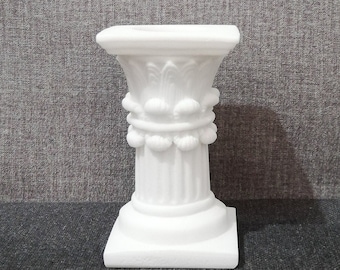 Può includere: Un piedistallo in ceramica bianca con una base quadrata e una parte superiore decorativa. Il piedistallo ha una colonna scanalata e una fascia di elementi decorativi.