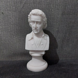 Può includere: Busto in marmo bianco di un uomo con capelli corti e ondulati. Il busto è su un piedistallo bianco.