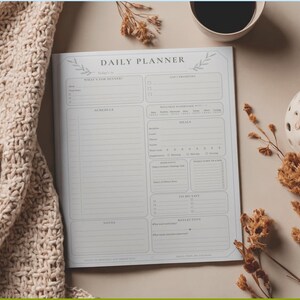 Puede incluir: Una p&aacute;gina de planificador diario con fondo gris claro y texto gris oscuro. El dise&ntilde;o incluye secciones para horario, lista de tareas, prioridades, bienestar, comidas y reflexi&oacute;n. El encabezado dice Daily Planner con ilustraciones de hojas.