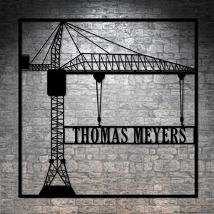 May include: Black metal silhouette of a construction crane with the name "THOMAS MEYERS" written on a banner hanging from the crane.