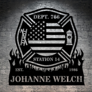 Könnte beinhalten: Schwarzes Feuerwehr-Emblem aus Metall mit einer amerikanischen Flagge, einer Leiter, einem Hydranten, Flammen und dem Text "DEPT. 766 STATION 14 EST. 1986 JOHANNE WELCH".