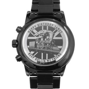 May include: Black wristwatch with a stainless steel strap. The watch face has a silver background with a black and white engraved image of a steam train with the text "Happy Birthday James Keep Rollin My Friend".
