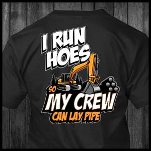 Könnte beinhalten: Schwarzes T-Shirt mit einem gelben Bagger und dem Text "I run hoes so my crew can lay pipe".