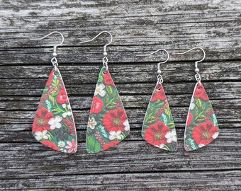 Puede incluir: Tres pares de pendientes colgantes con un patrón floral. Los pendientes están hechos de un fondo verde y blanco con flores rojas y detalles blancos. Los pendientes son de diferentes tamaños.