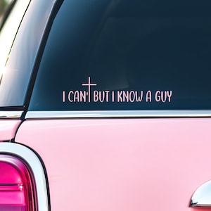 May include: Pink car with a window decal. The decal has the text "I CAN'T BUT I KNOW A GUY" with a cross symbol. The car's taillight and bumper are visible.