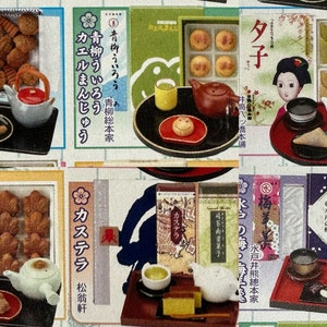 May include: Assortment of Japanese sweets and tea sets in miniature form. The sets include various types of traditional Japanese sweets, such as mochi, wagashi, and manju, along with miniature teacups, teapots, and trays. The packaging features Japanese text and illustrations.