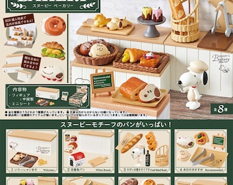 May include: A miniature Snoopy's Bakery playset featuring various baked goods, including bread, pastries, and donuts. The set includes Snoopy figurines and bakery display elements. The packaging features the Peanuts logo and Japanese text.