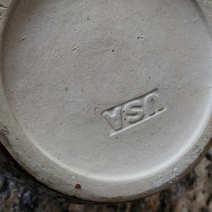 May include: Close-up of the bottom of a white ceramic jar with a brown rim. The jar has a "YSI" mark on the bottom.